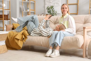 Oturma odasında cep telefonu kullanan güzel kız kardeşler.