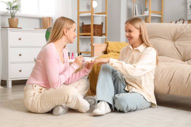 Güzel genç kız kardeşler oturma odasında manikür yapıyor.