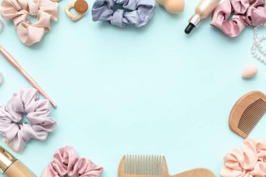 Mavi arka planda taraklı, kozmetik ürünlü ve aksesuarlı modaya uygun ipek tokalardan yapılmış çerçeve