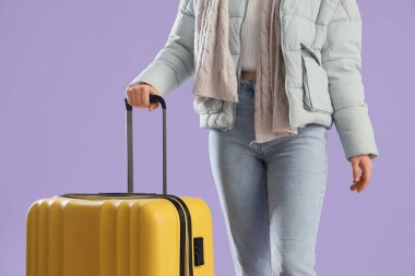 Mor arka planda bavulu olan güzel bir bayan turist, yakın plan.