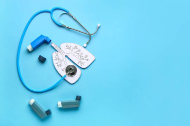 Mavi arka planda astım spreyi, kağıt akciğer ve steteskop bileşimi