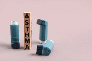 Modern inhalers and word ASTHMA on grey background clipart