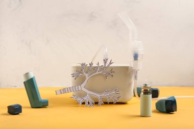 Sarı masasında astım spreyi ve kağıt ciğerli modern nebulizör.