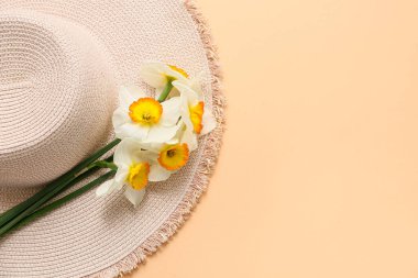 Güzel nergis çiçekleri ve turuncu arka planda hasır şapka