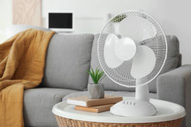 Oturma odasındaki sehpanın üzerinde modern elektrikli vantilatör var.