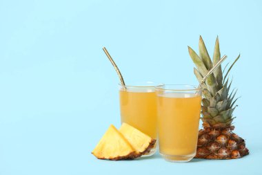 Mavi arka planda bir bardak taze ananas suyu.