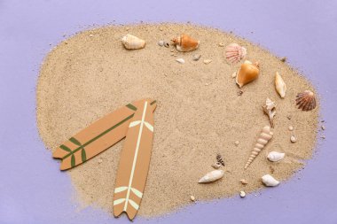 Renkli arka planda küçük sörf tahtaları, deniz kabukları ve kum kompozisyonu