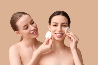 Sağlıklı ciltleri ve bej arka planda pamukları olan güzel, genç ve mutlu kadınlar.