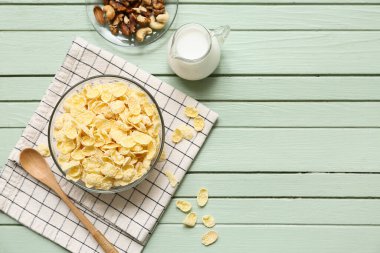 Peçete, yeşil ahşap arka planda mısır gevreği ve fındık dolu kaseler.