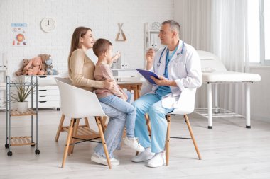 Çocuk doktorunda annesi olan küçük bir çocuk.