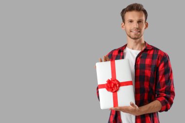 Gri arka planda hediye dizüstü bilgisayarı olan yakışıklı adam.