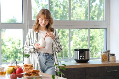 Mutfakta bal dolu kavanozu olan genç bir kadın.