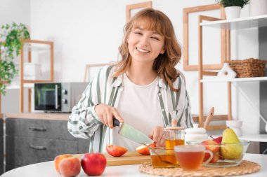 Mutfaktaki masada elma kesen kadın.