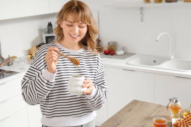 Mutfakta bal dolu kavanozu olan genç bir kadın.