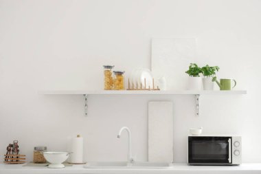 Fesleğen bitkileri ve mikrodalga fırını olan modern mutfağın içi.