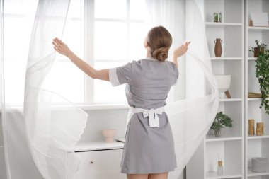 Otel odasının penceresinin yanındaki genç oda hizmetçisi.