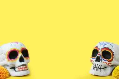 Sarı arka planda Meksika Ölüler Günü (El Dia de Muertos) için boyanmış kafatasları
