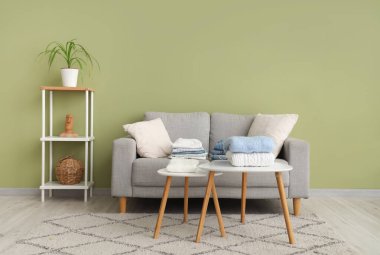 Şık oturma odasındaki masaların üstüne yığılmış temiz giysiler.