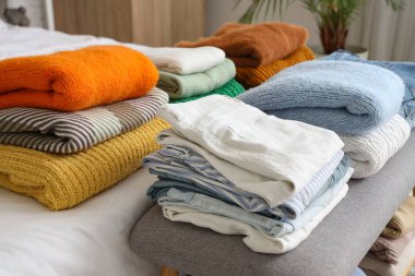 Yatağın üstüne yığılmış temiz giysiler, yakın plan.