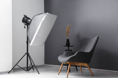 Koltuğu ve profesyonel ışıklandırma ekipmanlarıyla modern fotoğraf stüdyosu