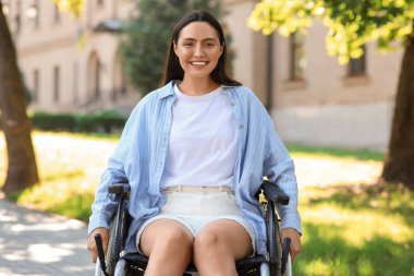 Dışarıda güneşli günlerin tadını çıkaran tekerlekli sandalyedeki genç kadın portresi.