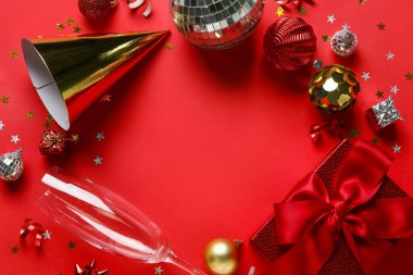 Noel toplarından yapılmış çerçeve, şampanya bardağı ve kırmızı arka planda hediye kutusu, yakın plan.