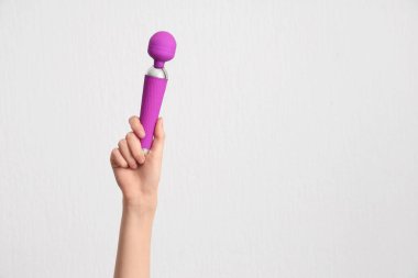 Beyaz arkaplanda vibratörü olan kadın eli