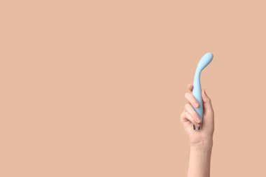 Kahverengi arka planda vibratörü olan bir kadın el.