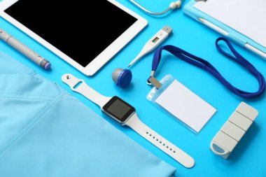 Tıp öğrencisi üniforması, malzeme ve modern cihazlar mavi arka planda, yakın plan.