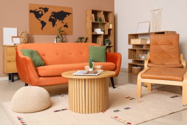 Bej duvardaki dünya haritası, kanepe, oturma odasının iç tarafında ayak sehpası ve masa olan koltuk.