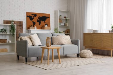 Kanepe, masa, çekmeceler ve oturma odasının iç tarafındaki duvardaki dünya haritası.