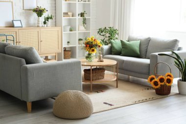 Sıcak kanepeler, kahve masası ve oturma odasında yabani çiçekler.