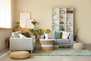 Rahat koltuklar ve vazodaki yabani çiçekler oturma odasının içindeki sehpanın üzerinde.