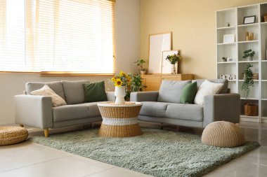 Rahat koltuklar ve vazodaki yabani çiçekler oturma odasının içindeki sehpanın üzerinde.