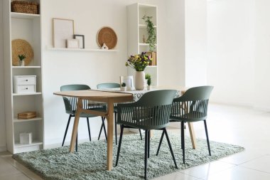 Yemek masasında vazoda yabani çiçekler ve odada sandalyeler.