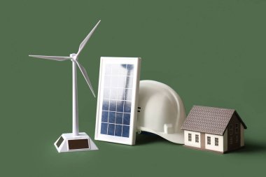 Rüzgar türbini modeli, ev, güneş paneli ve yeşil arka planda kalın başlık