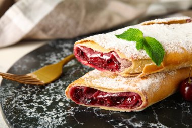 Arka planda siyah tabakta vişneli turta, yakın plan.