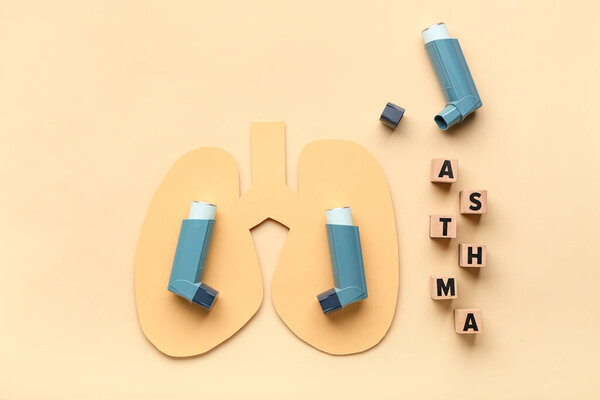 Ингаляторы, бумажные легкие и деревянные кубики с текстом ASTHMA на бежевом фоне