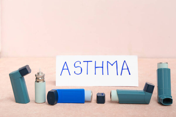 Современные ингаляторы и слово ASTHMA на розовом столе гранжа