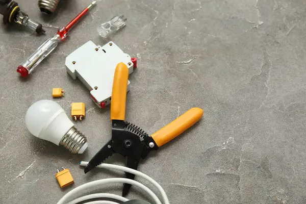 Gri grunge arka planında elektrikçi aletleri, ampul ve elektronik eşyalar