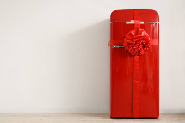 Big red fridge as gift near light wall