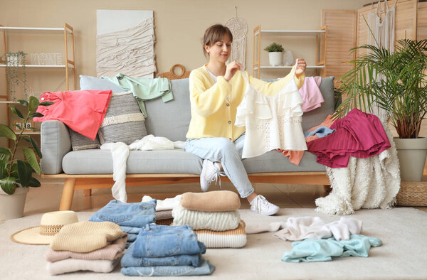 Красивая молодая женщина складывает чистую одежду дома