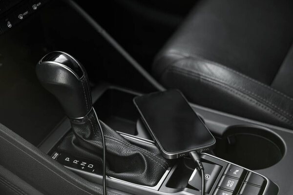 Мобильный телефон с зарядным кабелем в автомобиле, крупный план