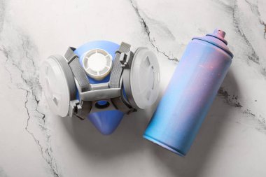 Mermer arka planda sprey boya kutusu ve solunum cihazı.