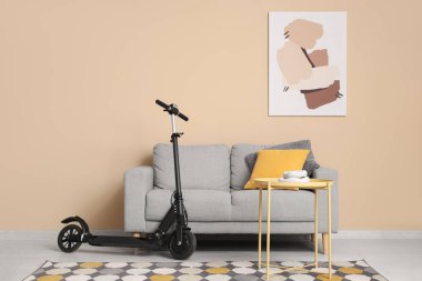 Oturma odasının içinde elektrikli scooter, kanepe ve masa var.
