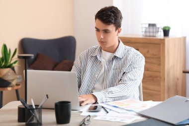 Erkek ekonomist ofiste dizüstü bilgisayarla çalışıyor.