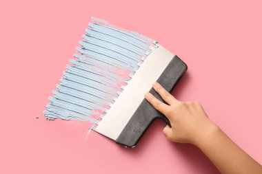 İşçi pembe arka plana macun koyuyor