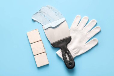 Mavi arka planda seramik ve eldiven olan macun bıçağı