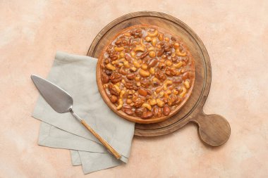 Farklı fındıklı ahşap bir tart tahtası ve bej arka planda karamel.