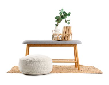 Vazoda dallar, kitaplar ve beyaz arka planda halı üzerine puf.